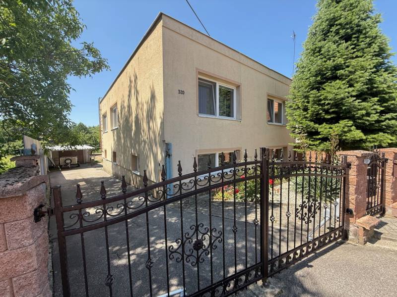 Brána a fasáda rodinného domu v Nemčiciach s ihličnanmi a záhradkou. Brána a fasáda rodinného domu v Nemčiciach s ihličnanmi a záhradkou.